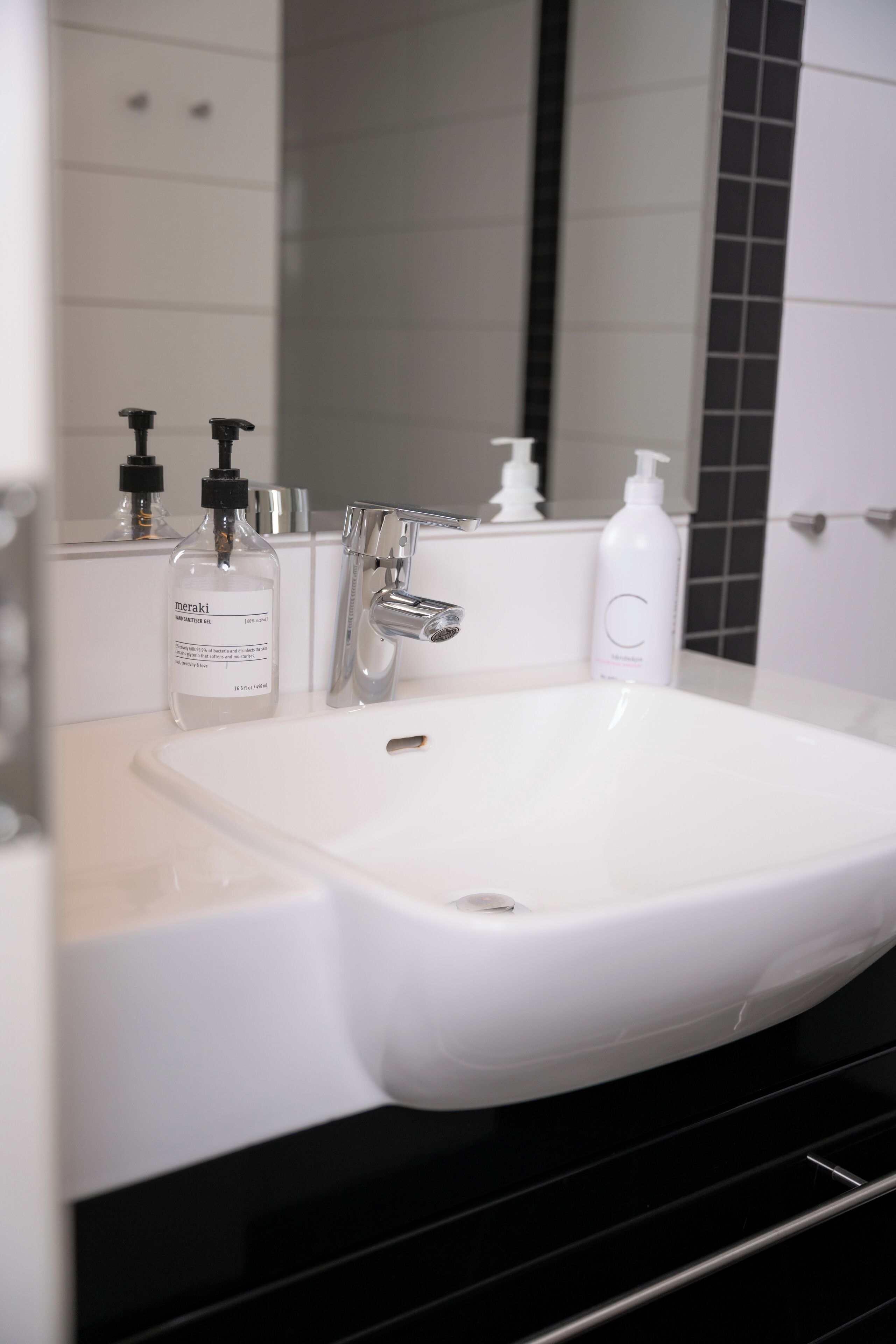 Un baño con un lavabo blanco, un espejo y dos botellas de jabón Meraki.