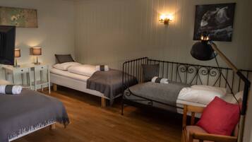 Quarto de hotel com duas camas de solteiro, uma cadeira, uma TV e um abajur.