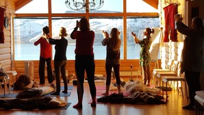 Een groep mensen in een kamer met grote ramen met uitzicht op een besneeuwd landschap.