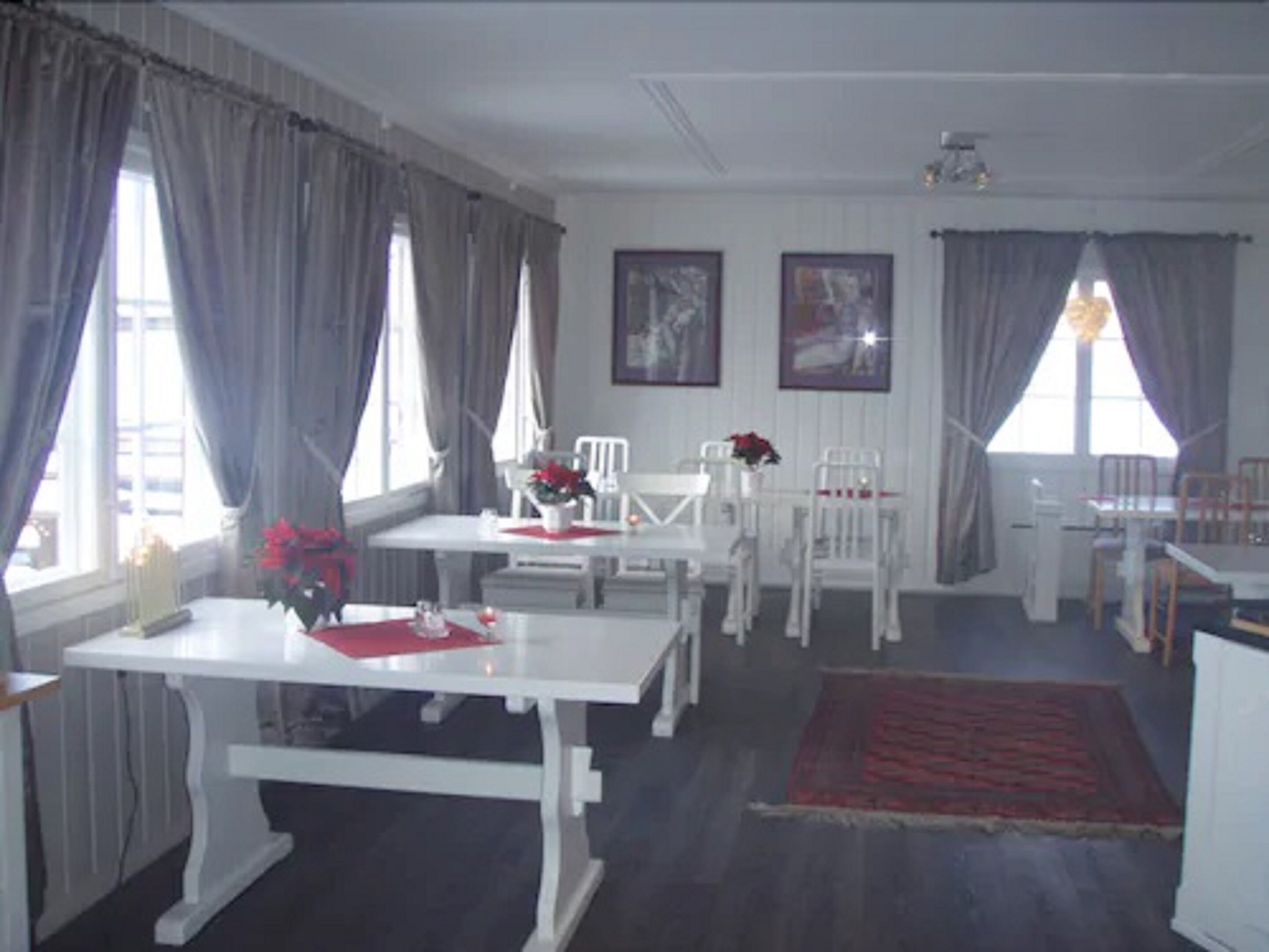 A dining area with white furniture, including a table and chairs, and a red rug on the floor.