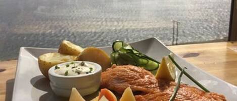 A plate of food with a view of a lake and mountains in the background.