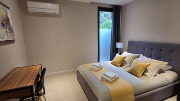 A modern hotel room with a bed, bedside table, chair, and a window with a view.