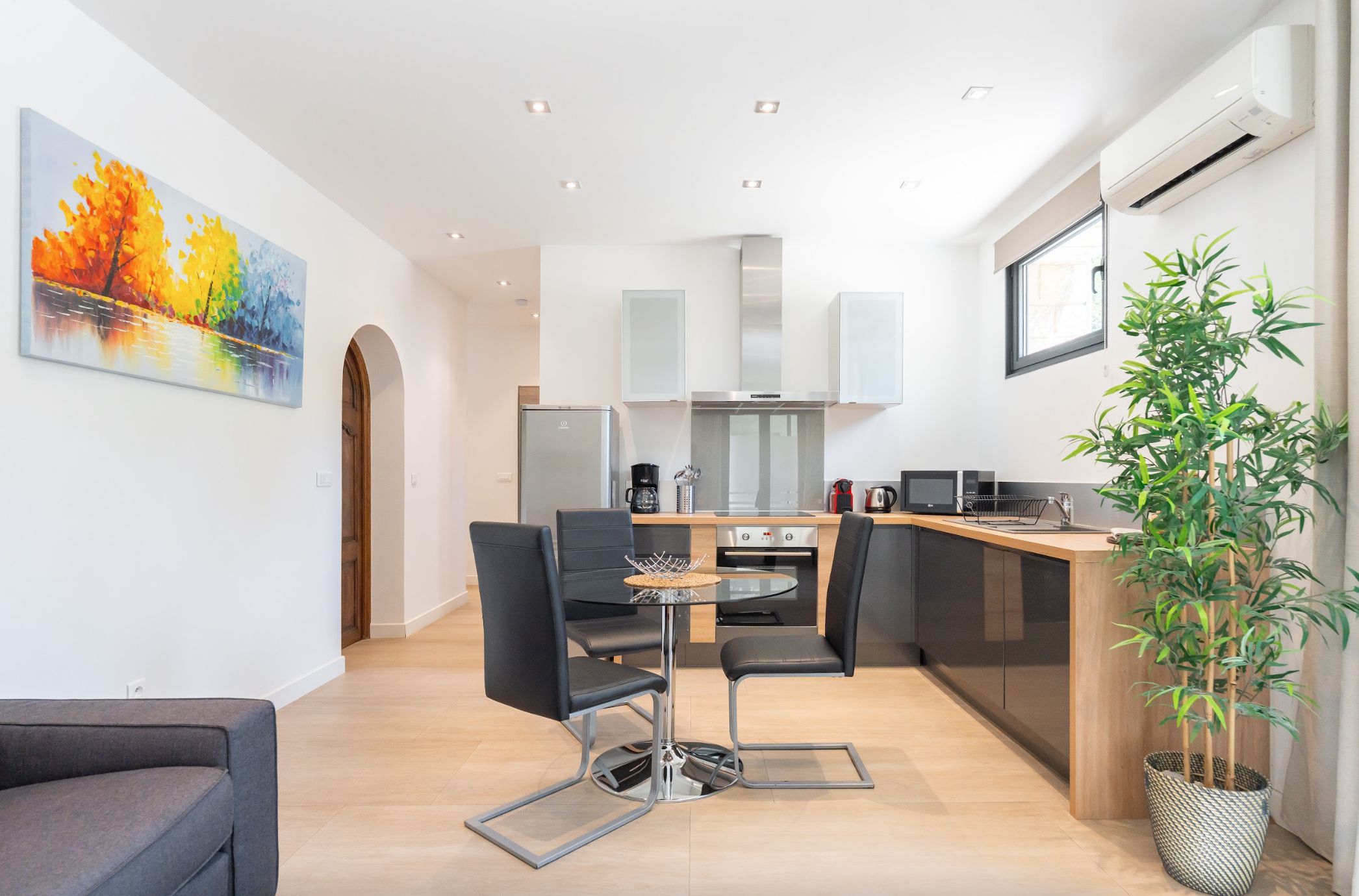 A modern kitchen with a dining area, a coffee machine, and a potted plant.
