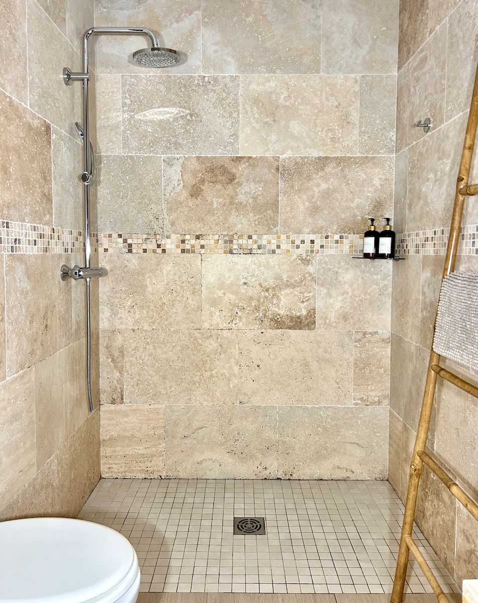 Een badkamer met een douche, toilet en betegelde vloer.
