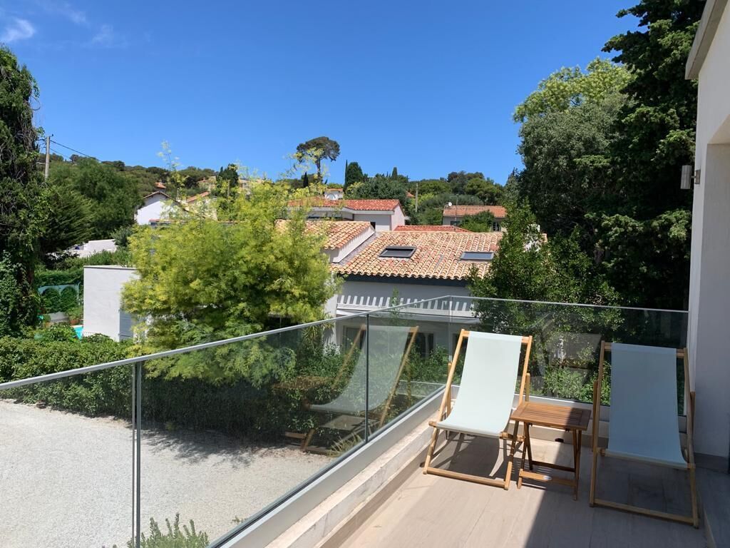A balcony with a glass railing, a wooden table, and a chair.
