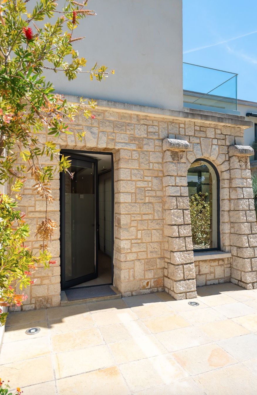 Un bâtiment en pierre avec une porte d’entrée en verre et une petite fenêtre.