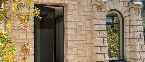 Un bâtiment en pierre avec une porte d’entrée en verre et une petite fenêtre.