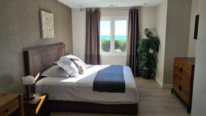A bedroom with a bed, a nightstand, a dresser, a window with curtains, and a potted plant. - Hôtel Particulier Cassis, Parking sécurisé, Piscine chauffée (Cassis)
