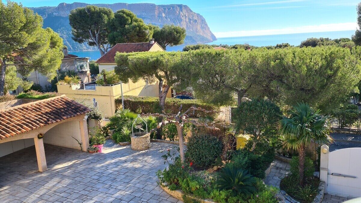 Un patio con una pérgola, plantas en macetas y vistas al mar y las montañas.