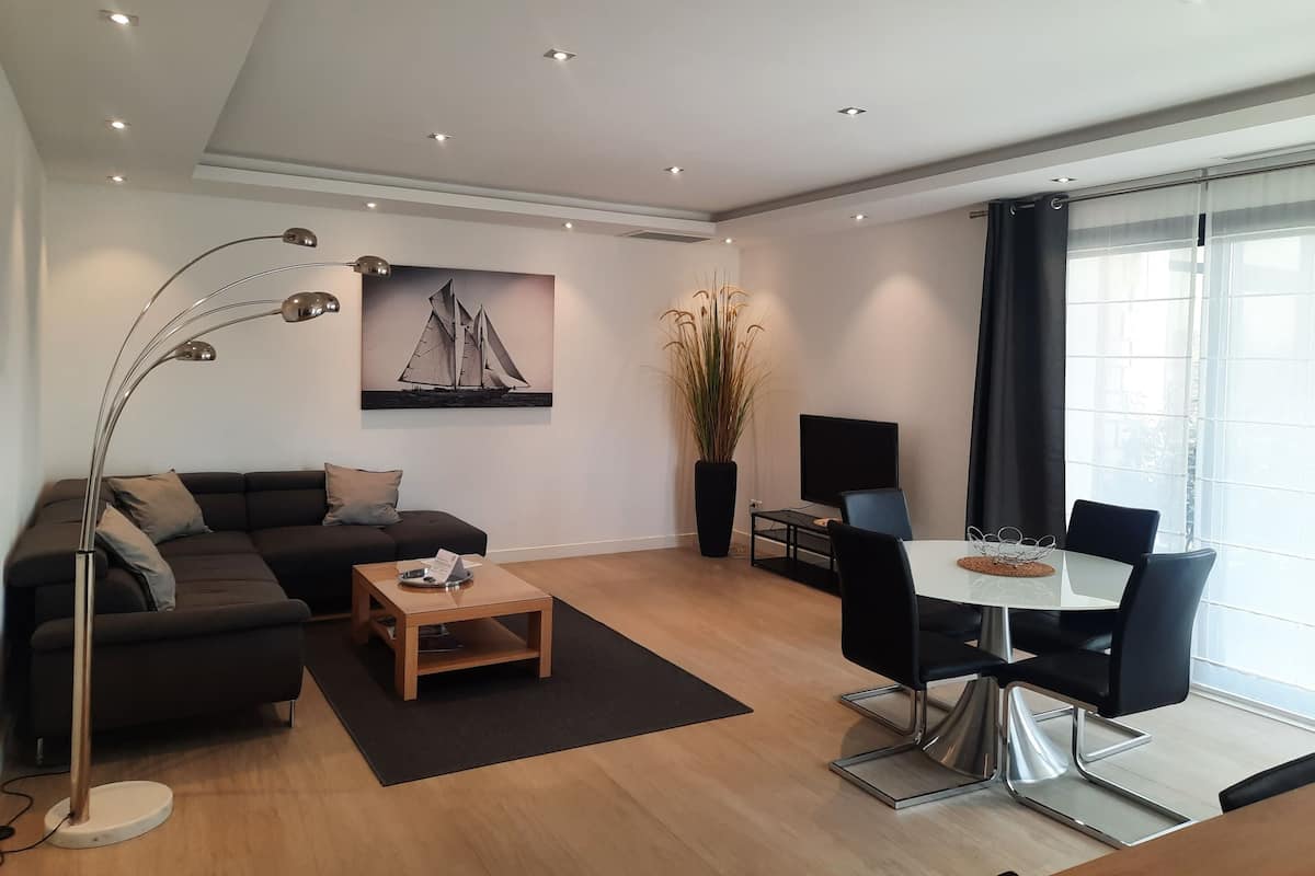 A modern living room with a sofa, coffee table, and a dining area with chairs and a table.