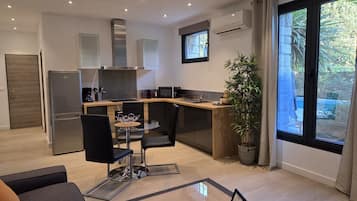 Una cocina moderna con zona de comedor, refrigerador, microondas y un amplio ventanal con vistas al verdor.
