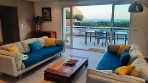 A living room with two sofas, a coffee table, and a view of the outdoors through large sliding doors. - Hôtel Particulier Cassis, Parking sécurisé, Piscine chauffée (Cassis)