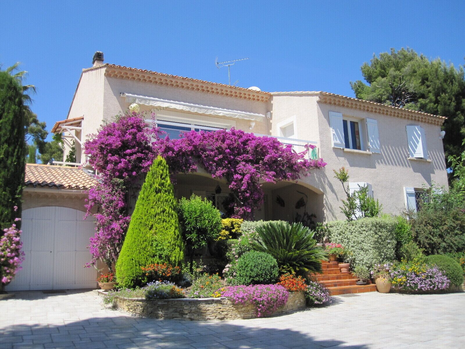 Ein zweistöckiges Haus mit Ziegeldach, Steinaußenwand und einem Garten mit verschiedenen Pflanzen und Blumen.