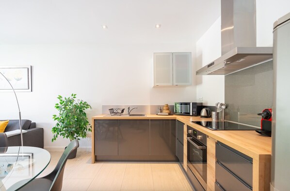 Una cocina moderna con encimera de madera, electrodomésticos de acero inoxidable y horno empotrado.