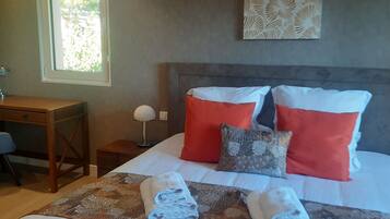 A hotel room with a bed, a desk, a chair, a lamp, and a window.