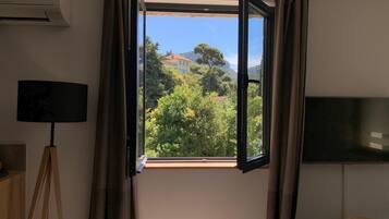 A room with an open window, a tripod lamp, and a flat-screen TV.