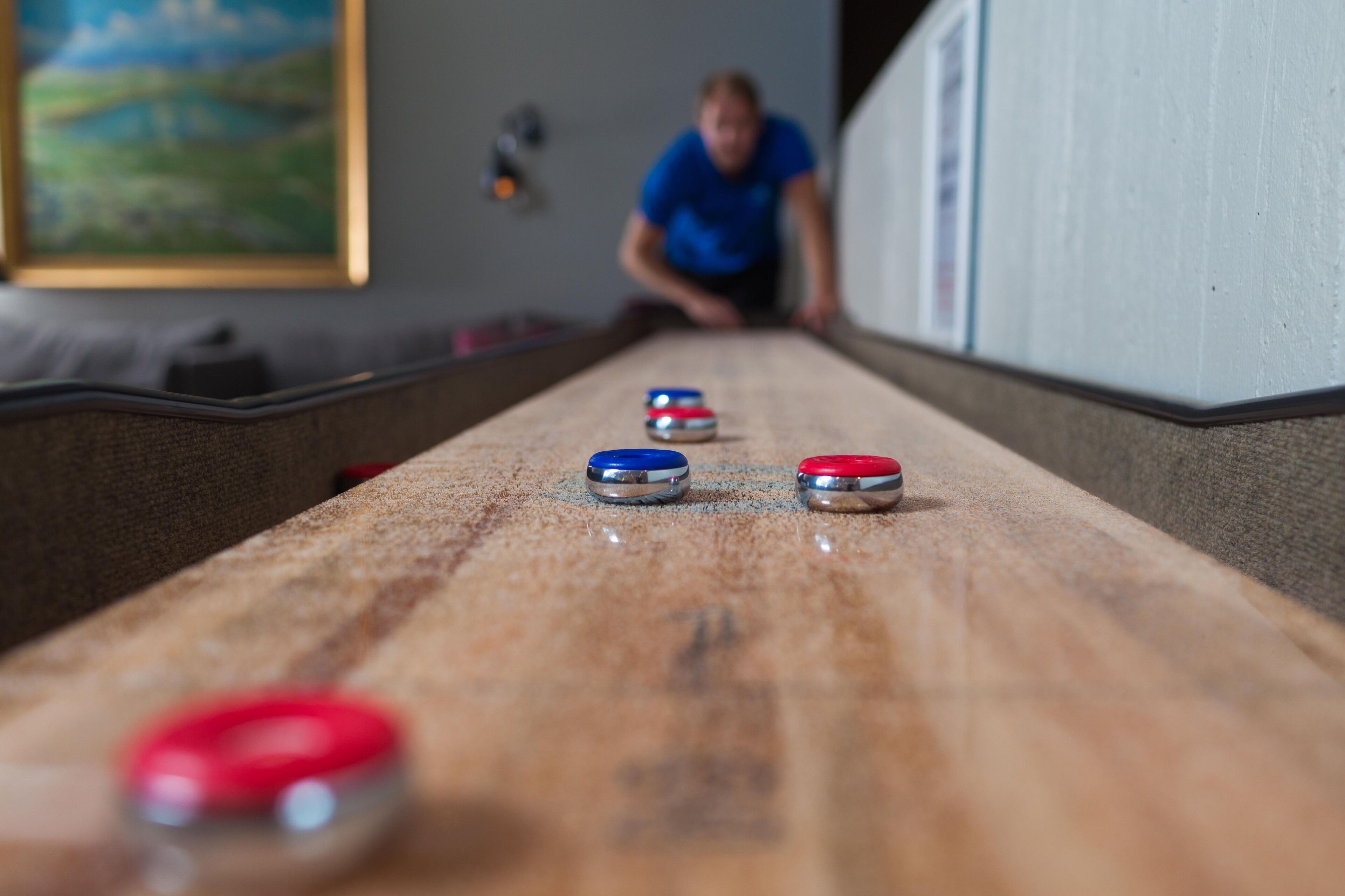 Una mesa de shuffleboard con discos rojos, azules y plateados.