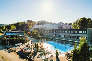 A hotel with a swimming pool, outdoor seating, and a large building in the background. - Bø Hotell (Midt-Telemark)