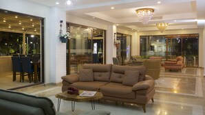 A spacious living area with a large brown sofa, a coffee table, and a dining area with blue chairs. - Villa Vanilla Hotel  (Istanbul)