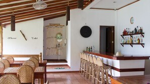 Un restaurante con mobiliario de madera, una zona de bar y una pared decorativa con indicaciones para ducha y baño.