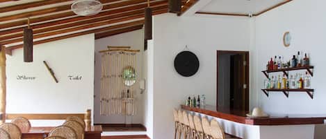 A restaurant with wooden furniture, a bar area, and a decorative wall with labels for shower and toilet.
