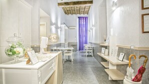 A hotel lobby with a reception desk, seating area, and a view of the reception counter. - History Suite (Rome)