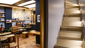 A cozy cafe with wooden furniture, a staircase, and a bar area with shelves and hanging lights. - Stay Inn Taksim Hostel (Istanbul)