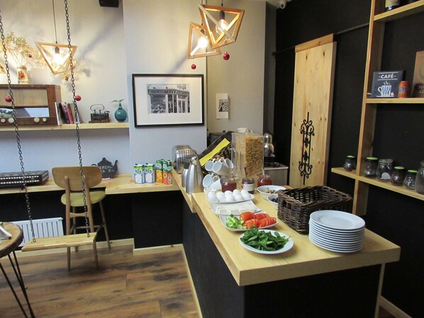 A breakfast bar with various food items, a vintage radio, and a framed black and white photo on the wall. - Stay Inn Taksim Hostel (Istanbul)