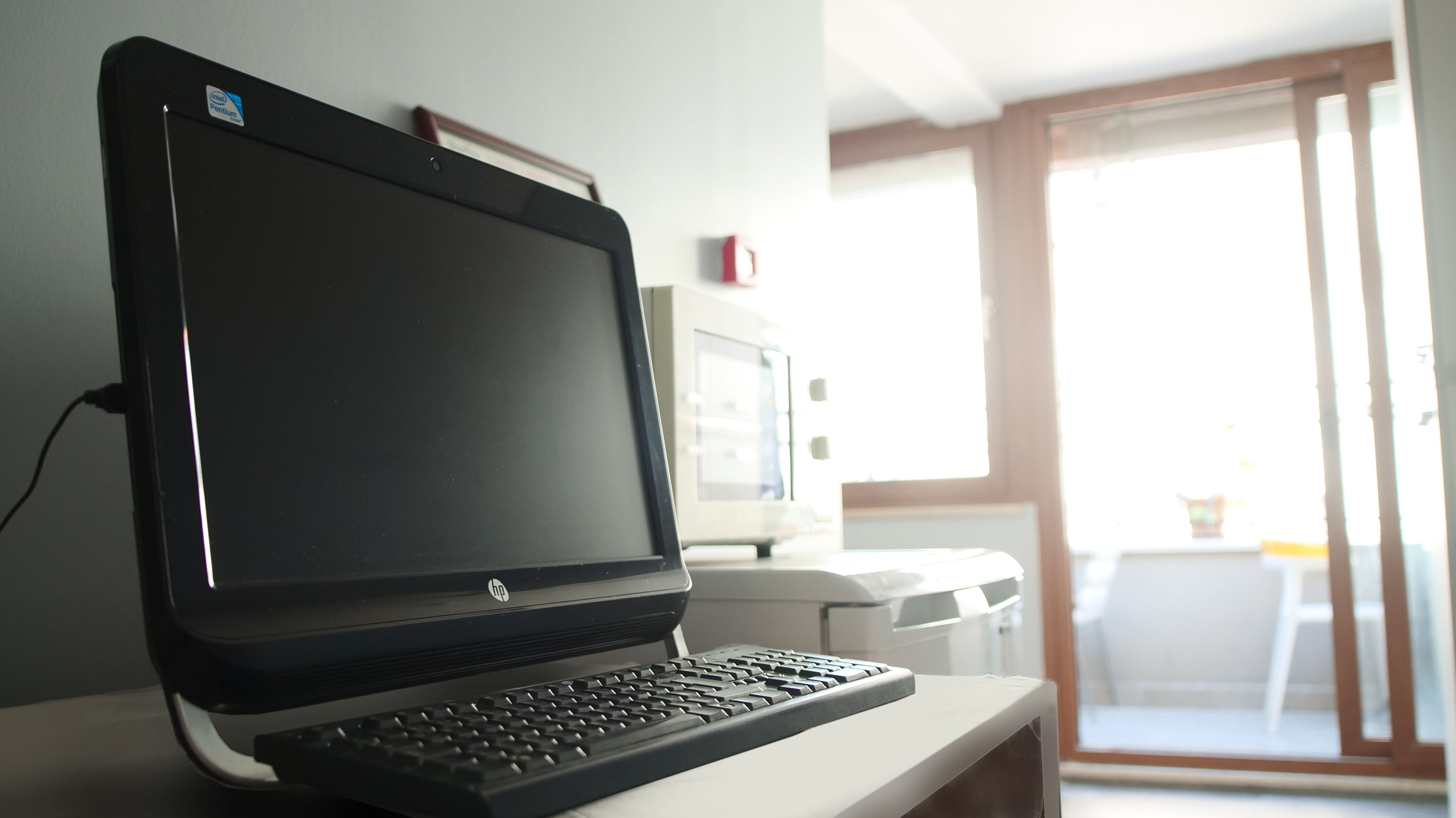 A laptop on a desk with a monitor, keyboard, and a sticker indicating an Intel processor.