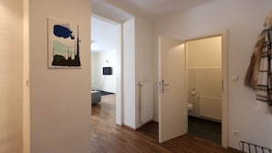 A hallway with a wooden floor, a door leading to a bathroom, and a wall-mounted artwork. - Heart of Vienna Residence (Vienna)