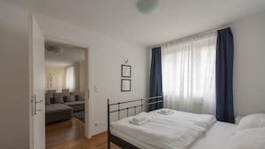 A bedroom with a bed, a sofa, and a door leading to another room. - Heart of Vienna Residence (Vienna)