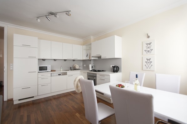 Kitchen features a microwave, oven, and coffee maker, with a dining table and chairs.