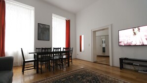 A living room with a dining table, chairs, a sofa, a TV, and a patterned rug. - Heart of Vienna Home (Vienna)