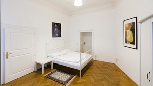 A bedroom with a bed, a bench, a door, and a light fixture. - Heart of Vienna Home (Vienna)