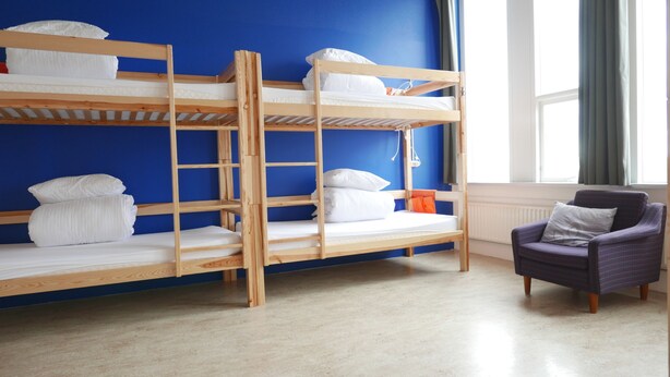 A bunk bed room with a blue wall, a window, and a chair.