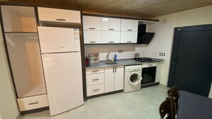 A compact kitchen with a refrigerator, washing machine, stove, and cabinets. - Beyoglu Pansiyon Apart (Kas)