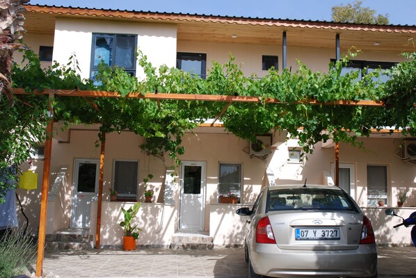 Um edifício com fachada branca, várias janelas e um carro estacionado na frente.