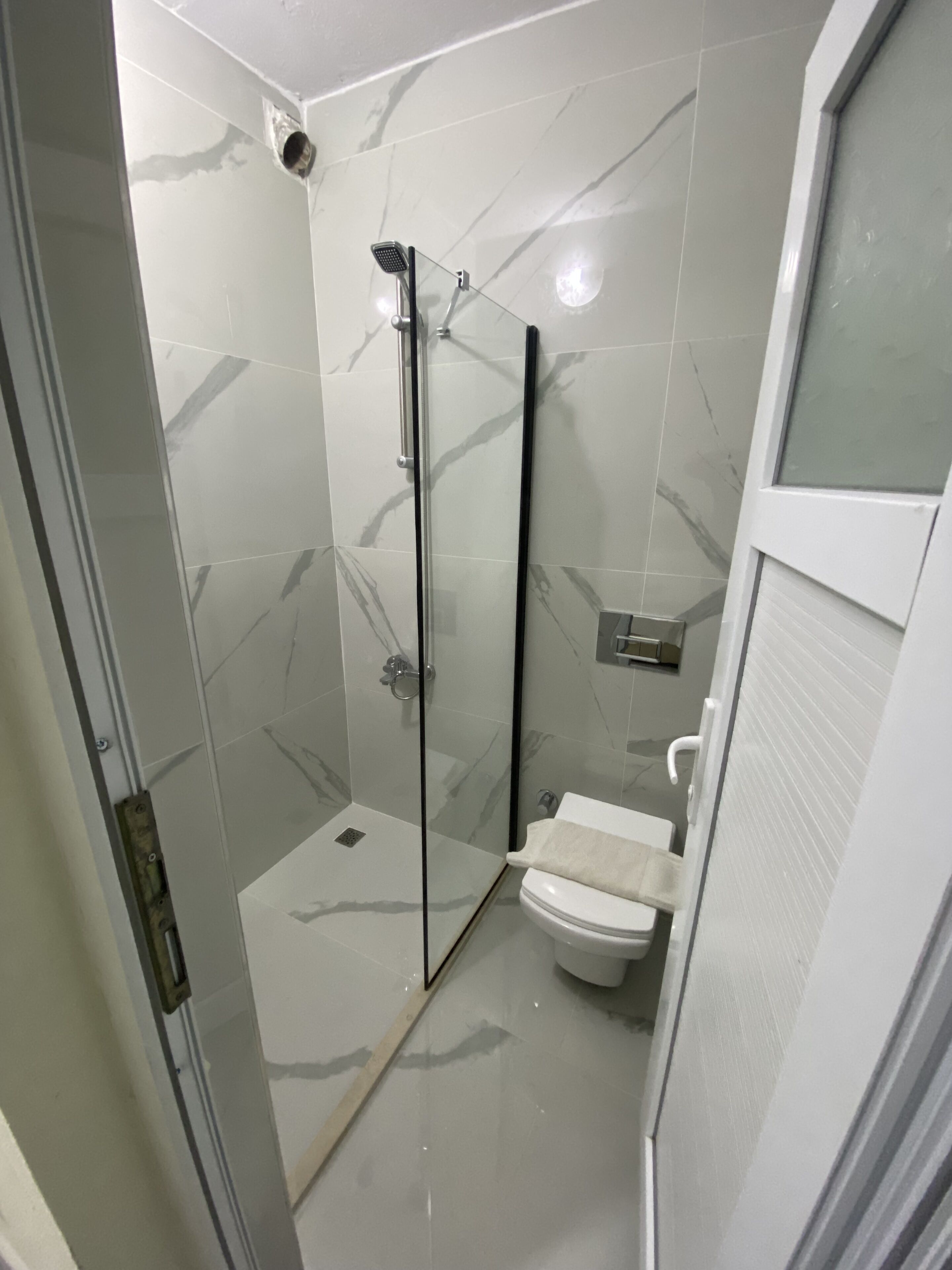 Un baño moderno con cabina de ducha de vidrio, inodoro y lavamanos.