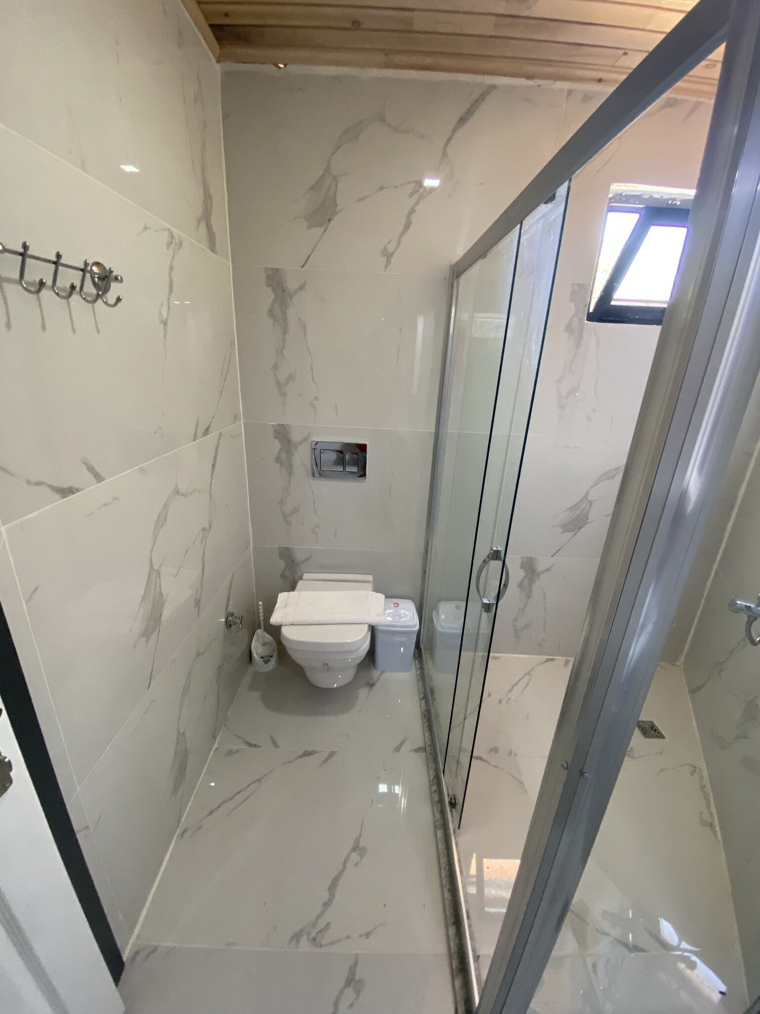 Une salle de bain comprenant des toilettes, une douche et un espace douche délimité par des parois en verre.