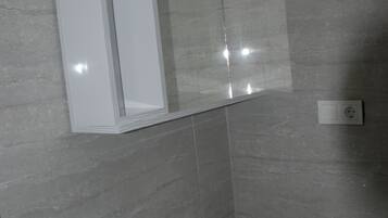 Un baño con lavamanos blanco, un espejo y una ventana.