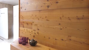 A wooden wall with a shelf holding a teapot and purple glasses.