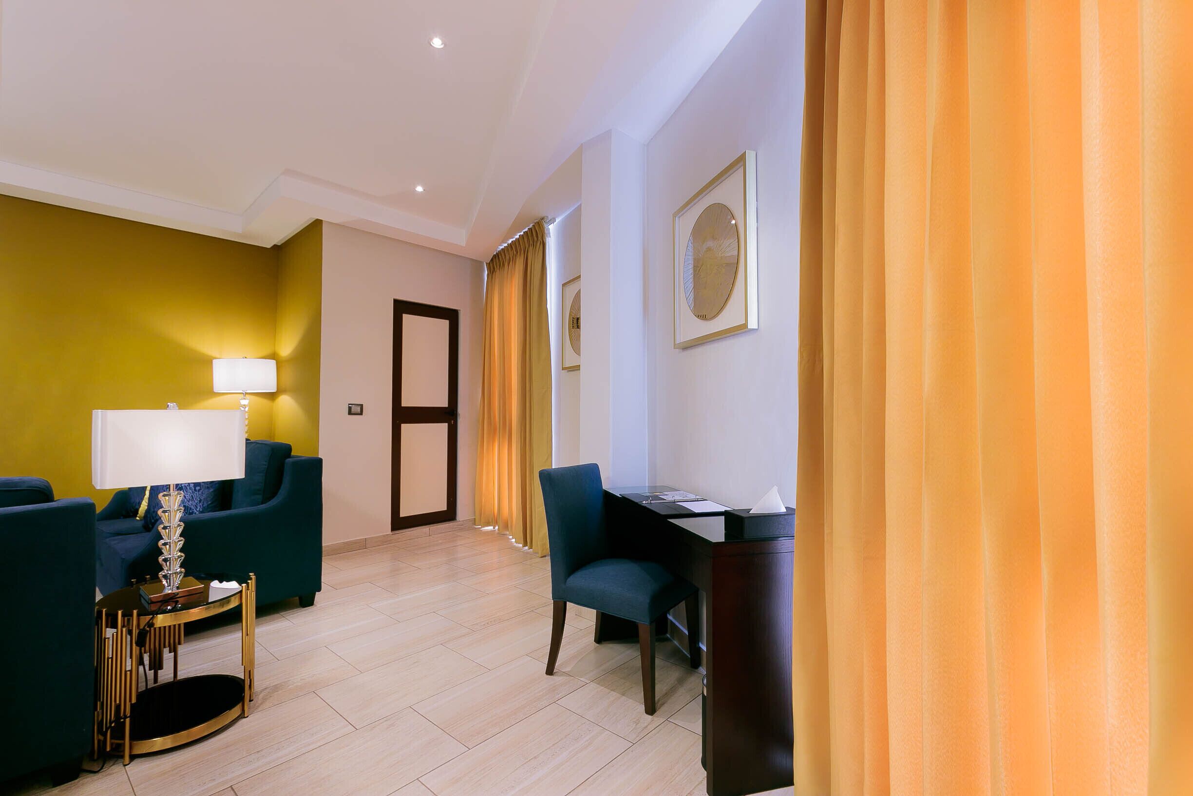 Ein Hotelzimmer mit einer Couch, einem Schreibtisch, einer Lampe und einem Sessel.