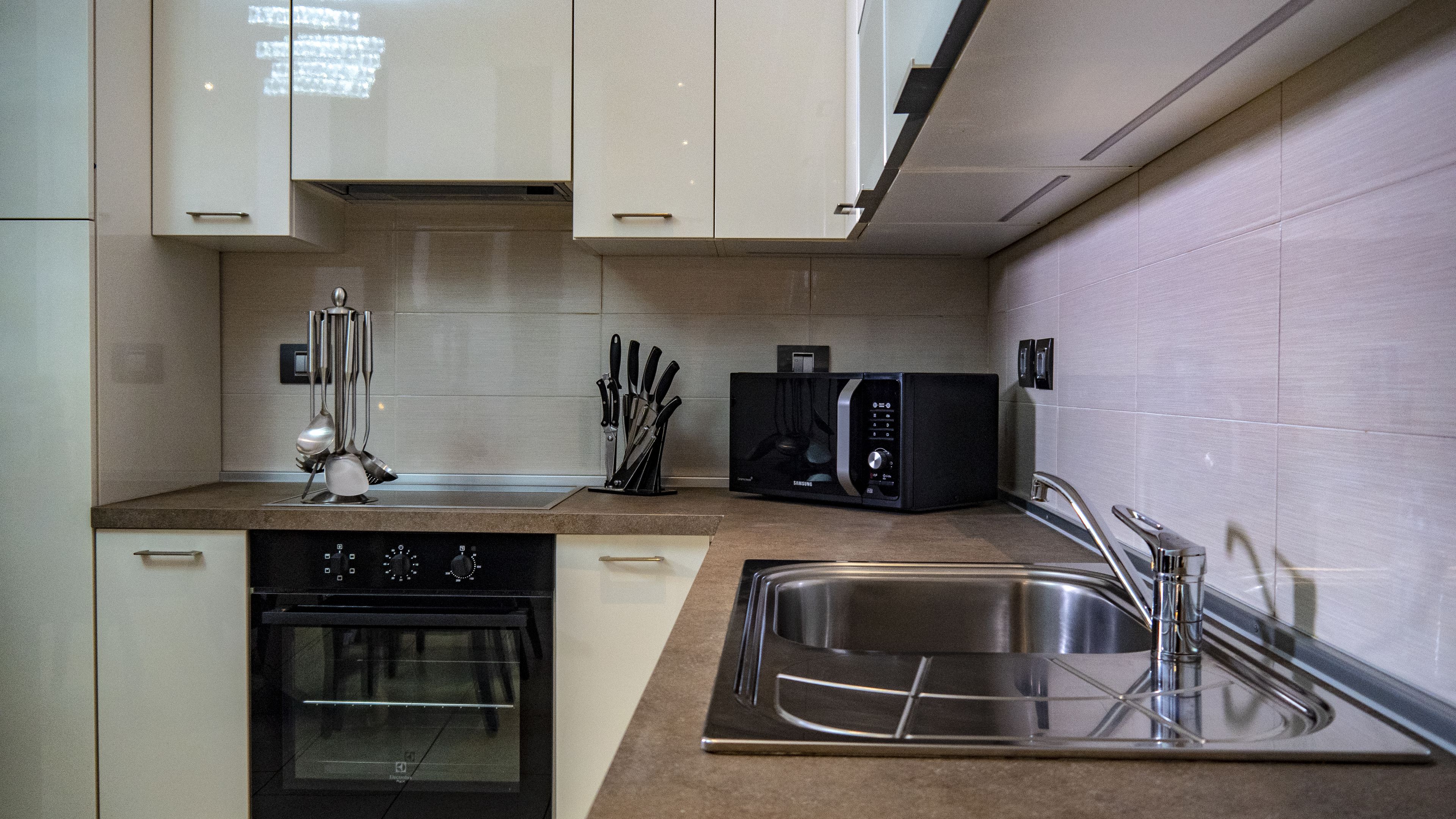 A modern kitchen with a built-in oven, microwave, and stainless steel sink.