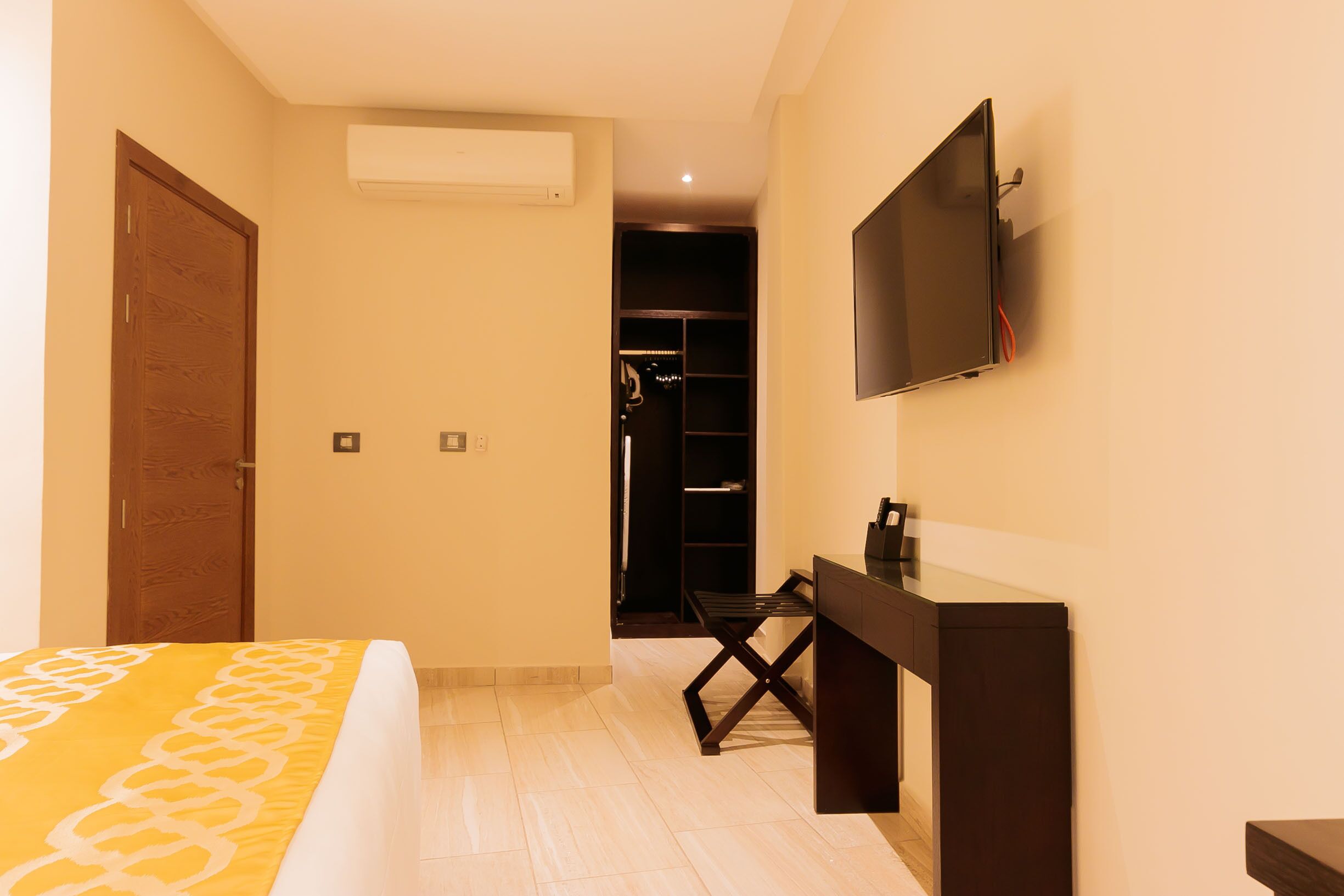 Una habitación de hotel con cama, escritorio, televisor y armario.