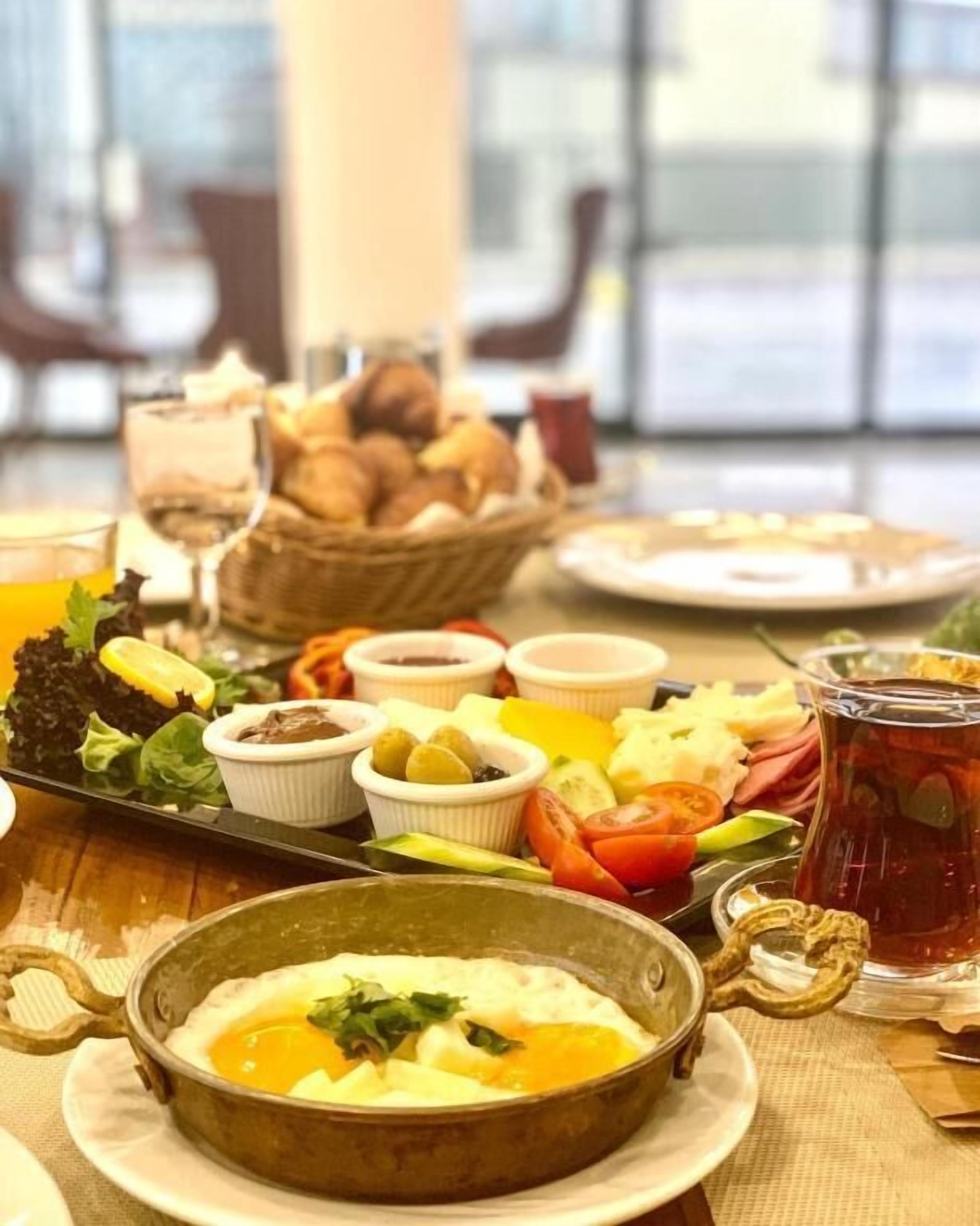 A breakfast buffet with various dishes, including a bowl of soup, fruit, and bread.