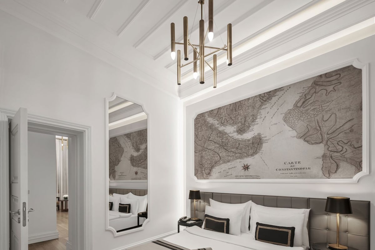 A modern bedroom with a large bed, a map on the wall, and a chandelier.