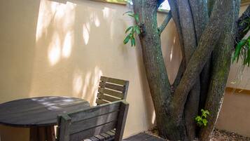 Um banco e uma mesa de madeira encostados em uma parede com um grande tronco de árvore.