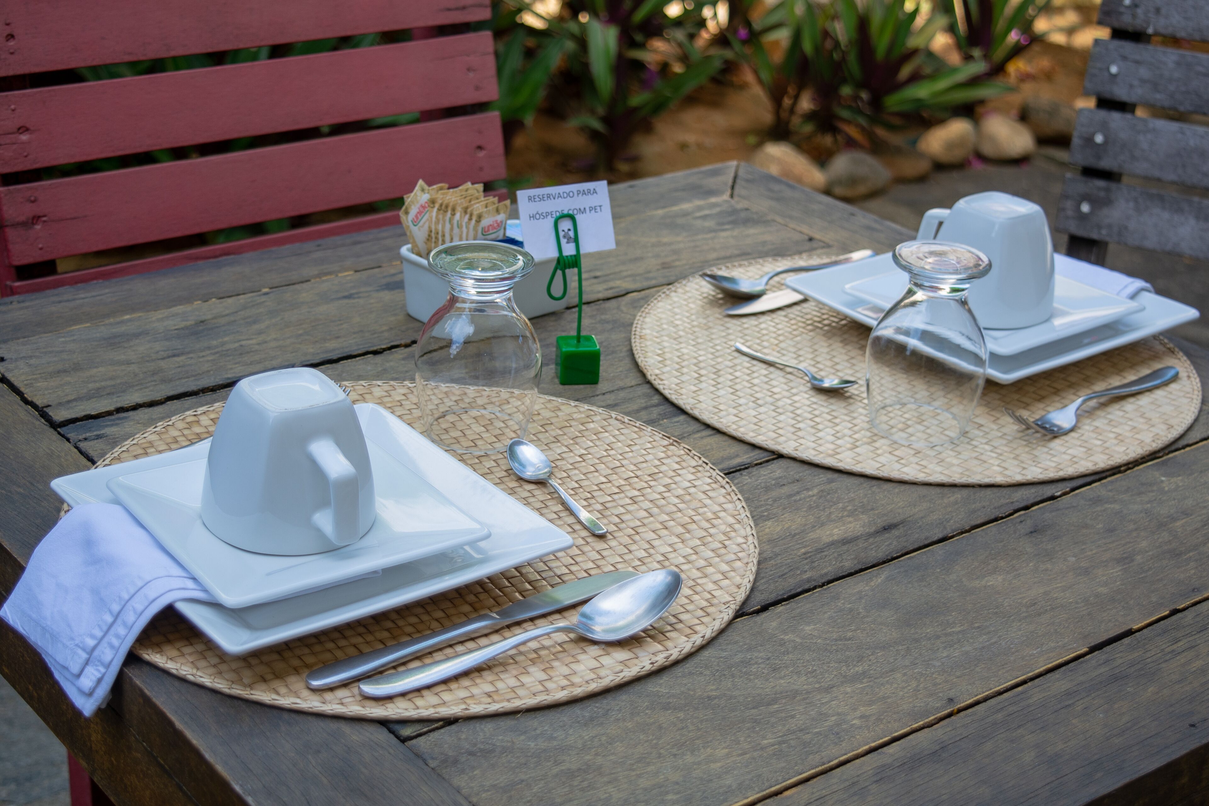 A wooden table set with white plates, silverware, and a glass pitcher, with a sign indicating a reserved table.