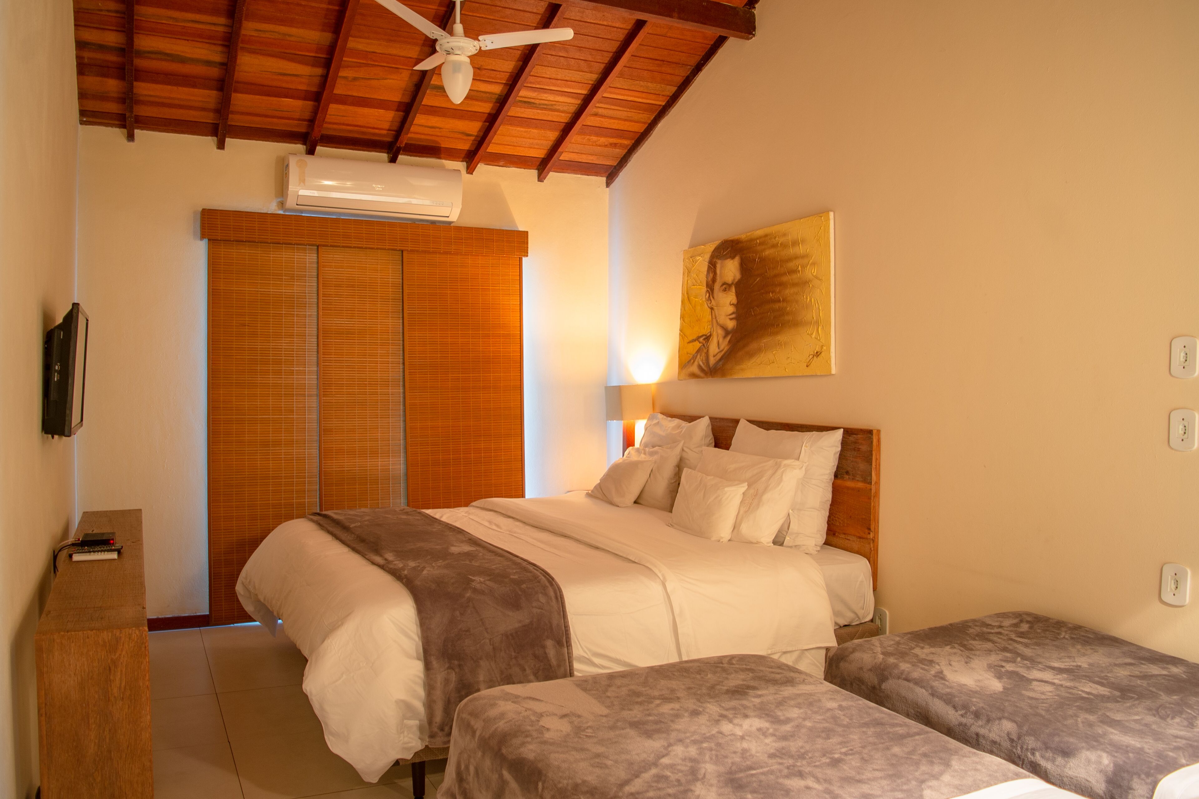 A bedroom with a bed, two bedside tables, a ceiling fan, and a painting on the wall.