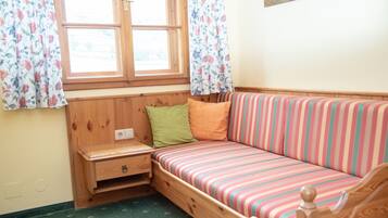 Una habitación acogedora con un banco de madera y un sofá colorido a rayas.